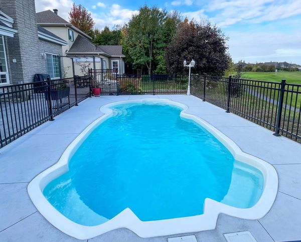 piscine atypique en fibre de verre aménagé trottoir béton, clôture ornemental