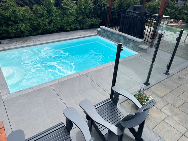 piscine en fibre de verre aménagé trottoir béton, bullnose, pierre de couronnement, clôture verre 