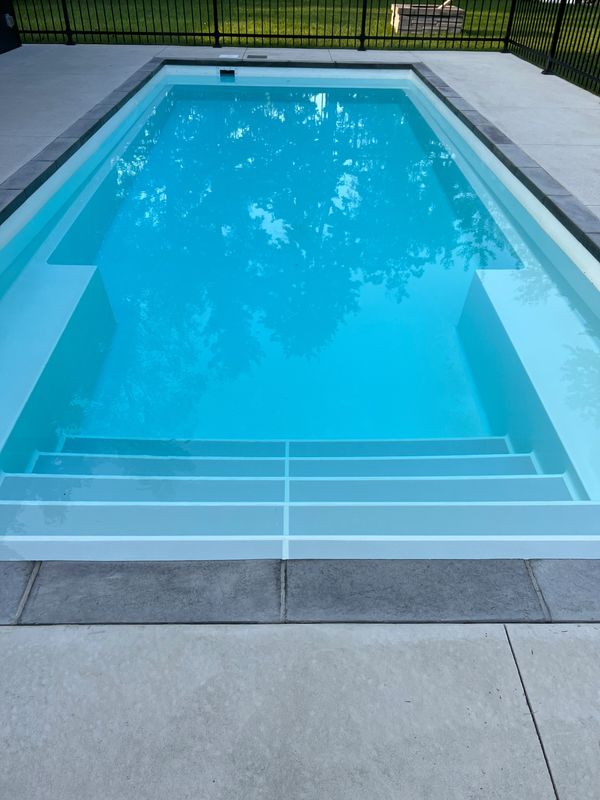 piscine en fibre de verre aménagé trottoir béton, bullnose, pierre couronnement, clôture ornemental