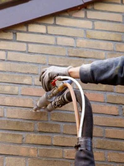 Technician using industrial vacuum for cavity wall insulation