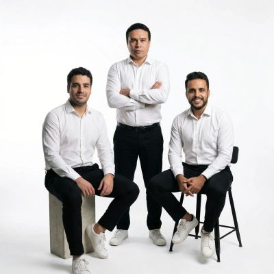 Three men in white shirts and black pants posing confidently in a studio.