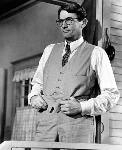 Actor in a waistcoat and trousers, standing on a porch looking into the distance
