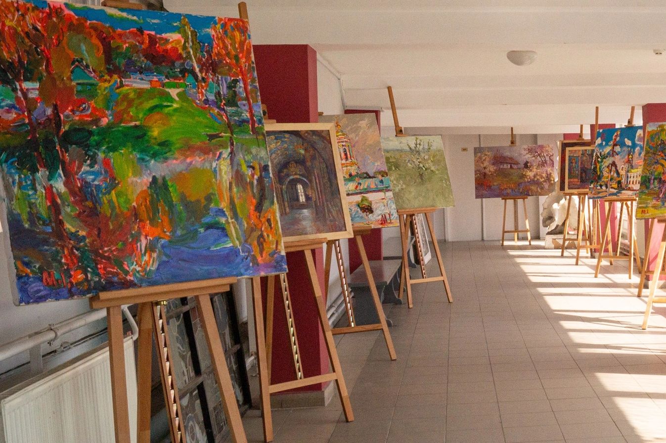 Art exhibition with colorful paintings on easels.