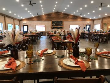 Rustic dining hall set for an event with autumn-themed table settings.