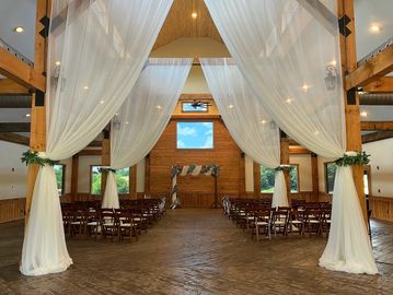 Grand ballroom with vaulted ceilings, exposed wooden beams, and expansive windows 