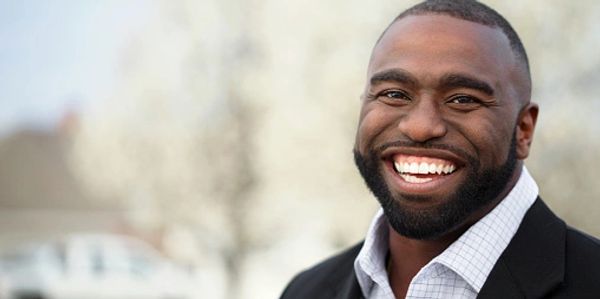 Smiling man in business attire outdoors.