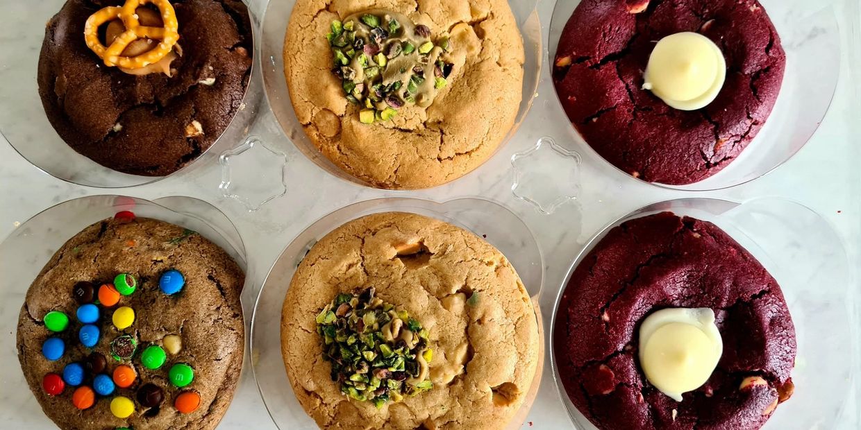 Six assorted gourmet cookies with various toppings.