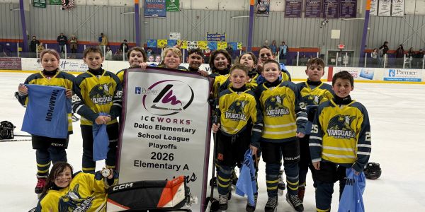 Youth hockey team celebrates playoff banner on ice rink.