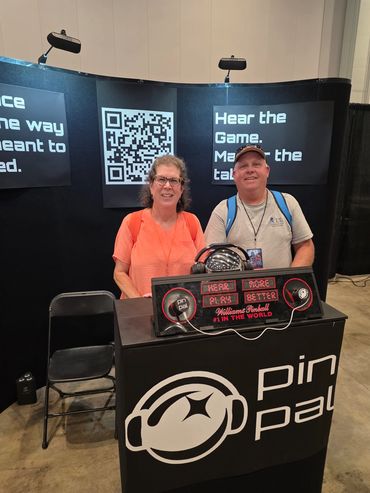 Two people at a promotional booth with a sign for Pinball.