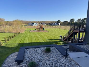 Wide backyard with playground and neatly mowed lawn.