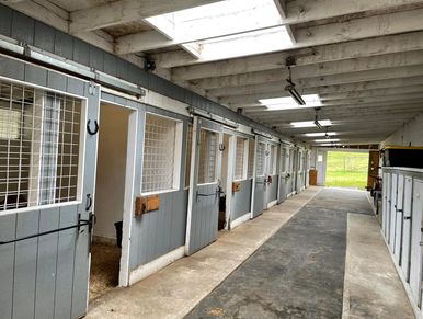 Interior of a stable with empty horse stalls.