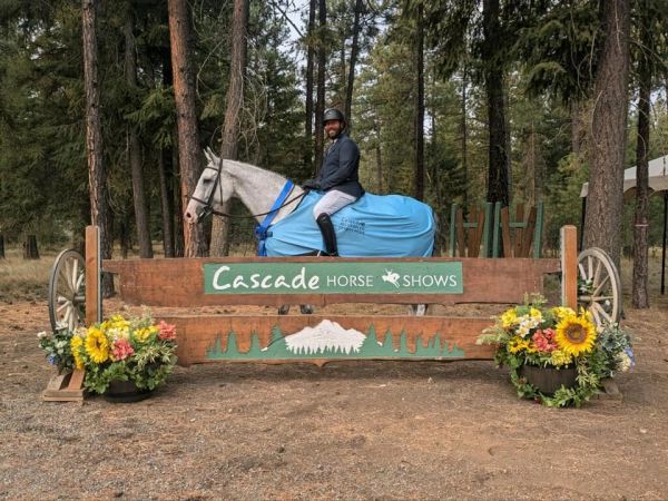 Rider on gray horse at Cascade Horse Shows jump.