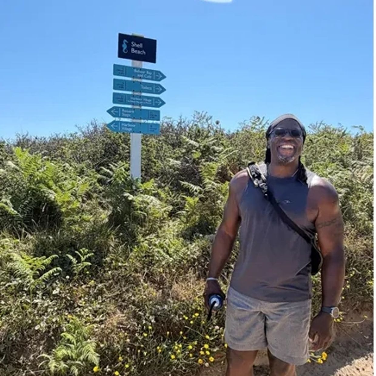 Man smiling near Shell Beach signpost.