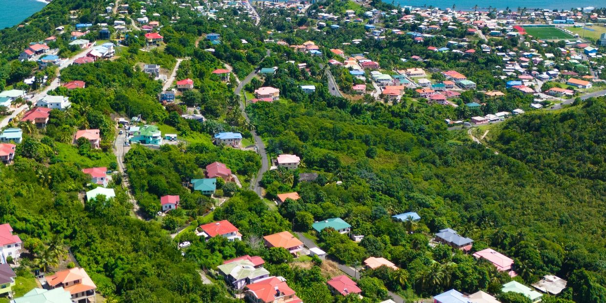Aerial view of a coastal town with colorful houses and lush greenery.