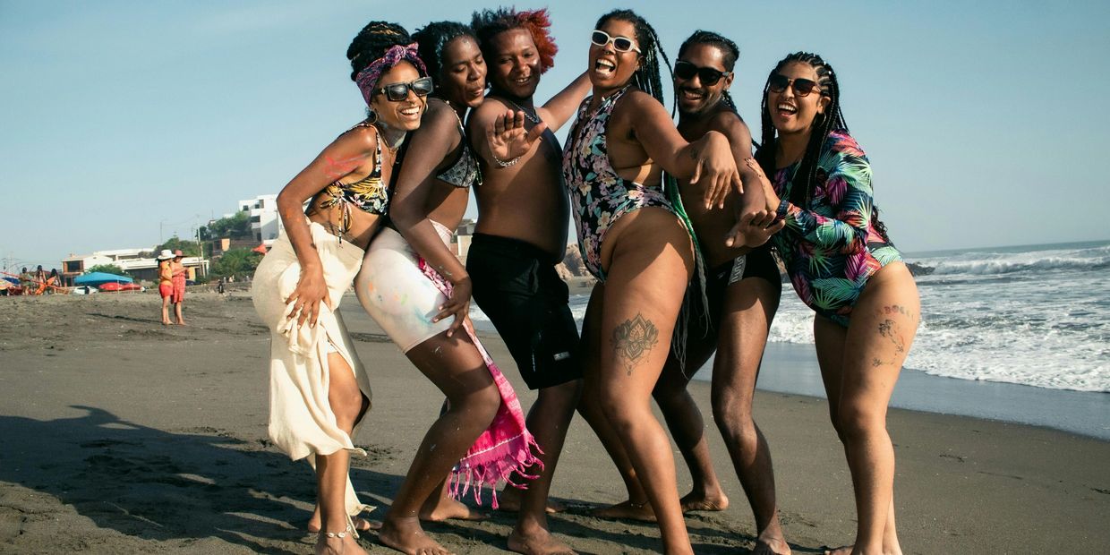 Group of six friends joyfully posing on a sunny beach.