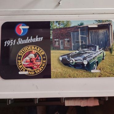 1951 Studebaker car and vintage service logo on a sign.