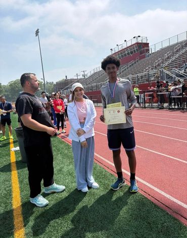 Young athlete receiving an award on a track field.