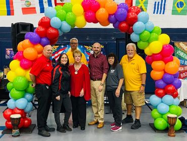 Group standing under colorful balloon arch.