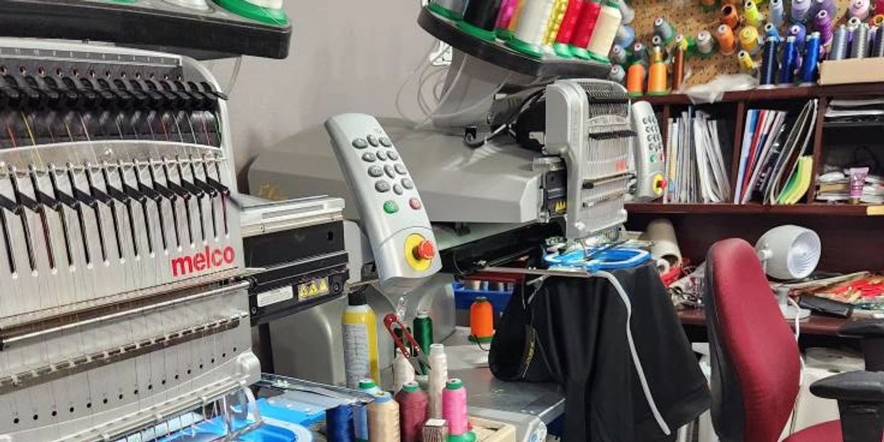 Industrial embroidery machines and colorful threads in a sewing workspace.