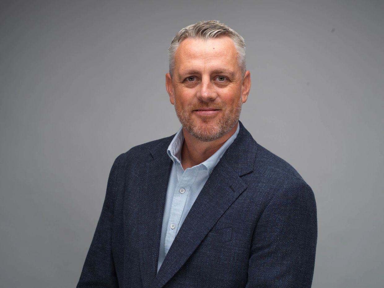 Confident middle-aged man in a blue blazer smiles at the camera.