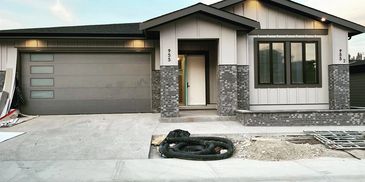 Modern house exterior with garage and front porch under construction.