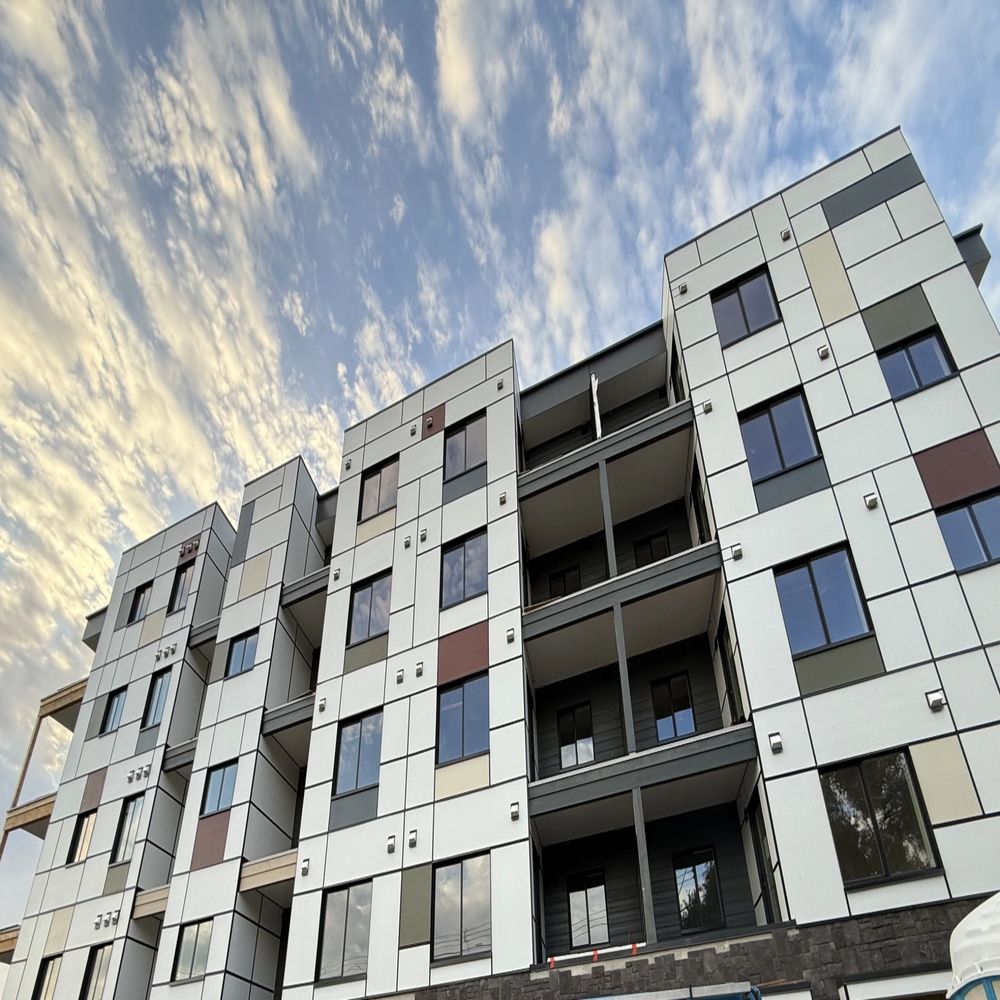 Modern apartment building with a patterned facade under a cloudy sky.