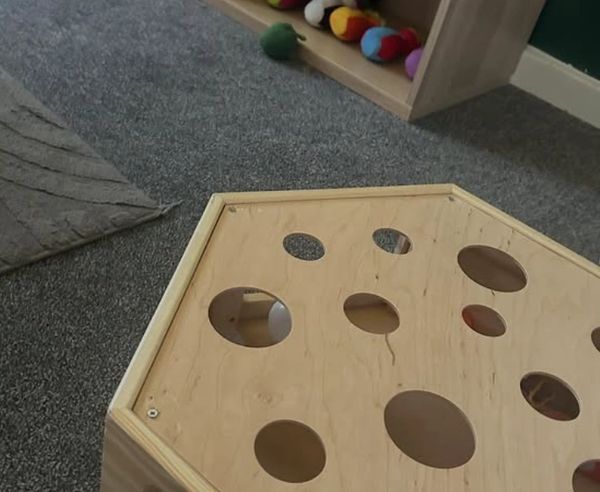 Wooden play structure with circular holes for toys or balls.