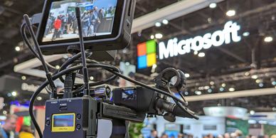 Professional Sony camera setup filming at a Microsoft event with a crowd in the background.