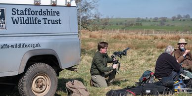 Wildlife filmmakers filming a nature scene next to a Staffordshire Wildlife Trust vehicle.