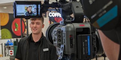 A man being filmed with a professional Sony camera indoors.
