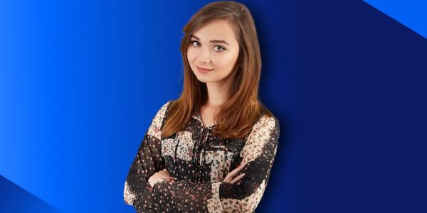 Young woman with crossed arms smiling against a blue background.