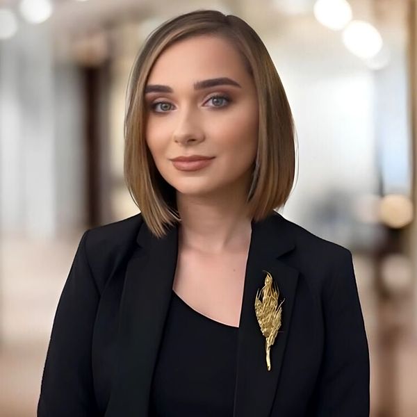 Professional woman in a black blazer with a golden brooch.