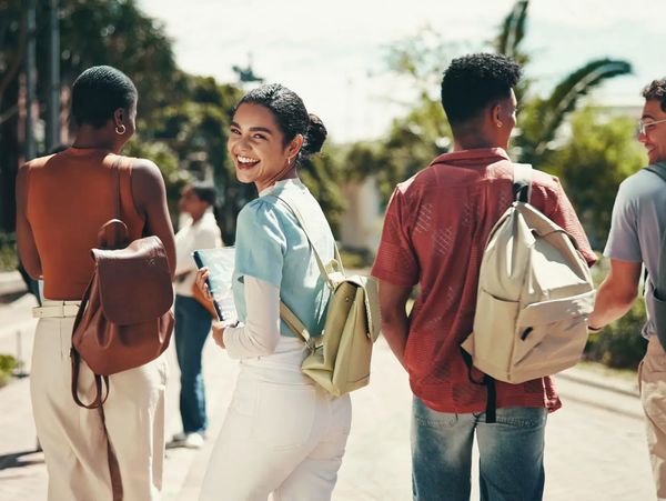 Four students walking outdoors, with one smiling at the camera.