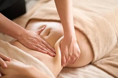 Hands giving a relaxing abdominal massage on a covered body.