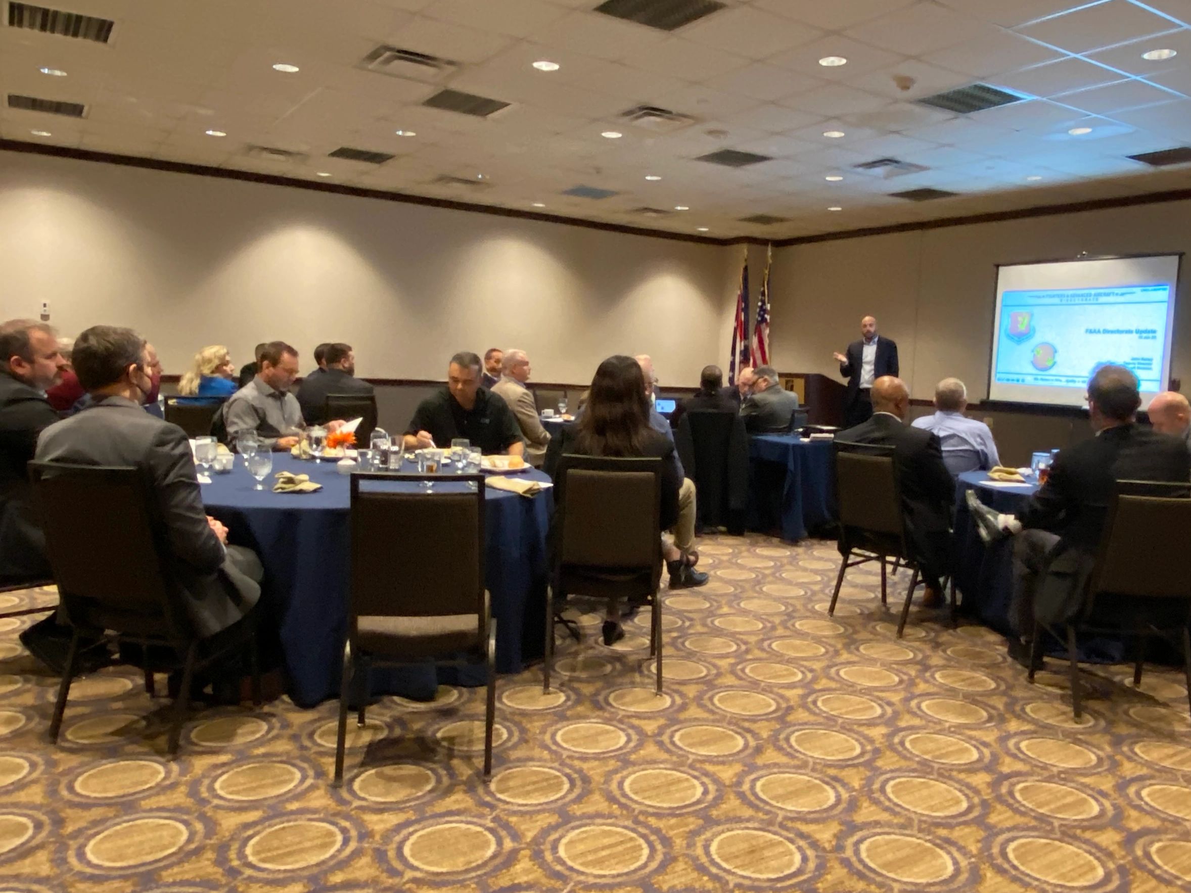 A presenter and an audience sitting at tables