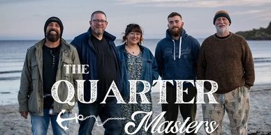 Five people standing together on a beach with "The Quarter Masters" text overlay.