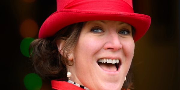 Woman wearing a bright red hat smiling joyfully.