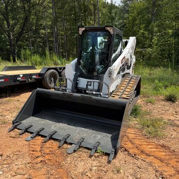 Compact tracked skid steer loader on dirt.