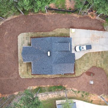 Aerial view of a house with a driveway and a parked car.