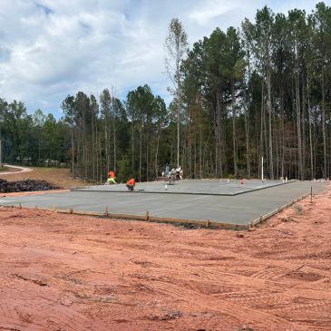 Workers smoothing a freshly poured concrete slab outdoors.