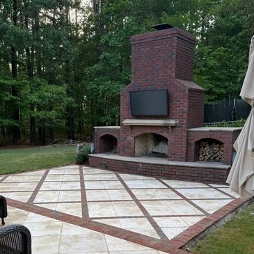 Outdoor brick fireplace with mounted TV in backyard.