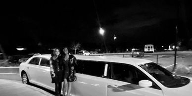 Two girls celebrating homecoming with a picture in front of a Chrysler 300 stretch Limousine