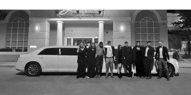 Group of 9 people taking a picture in front of a 10 passenger stretch limousine