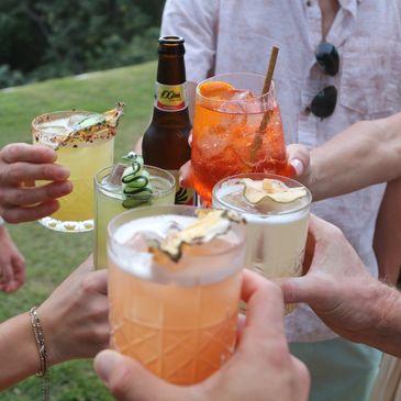 Group toast with colorful drinks outdoors.