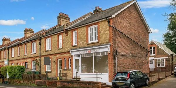 Row of brick townhouses with a small gallery storefront and parked cars.