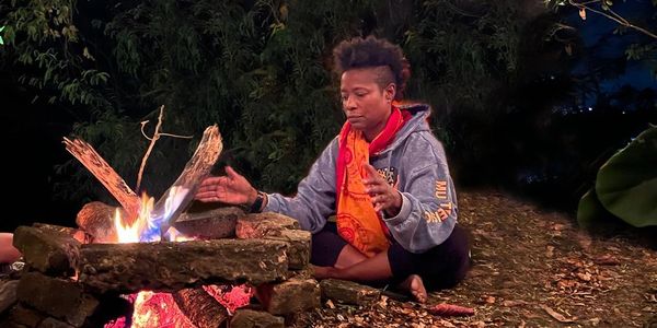 Person warming hands by a campfire at night outdoors.