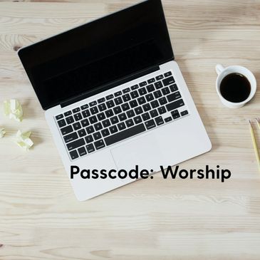 Laptop on wooden desk with coffee and note saying 'Passcode: Worship'.