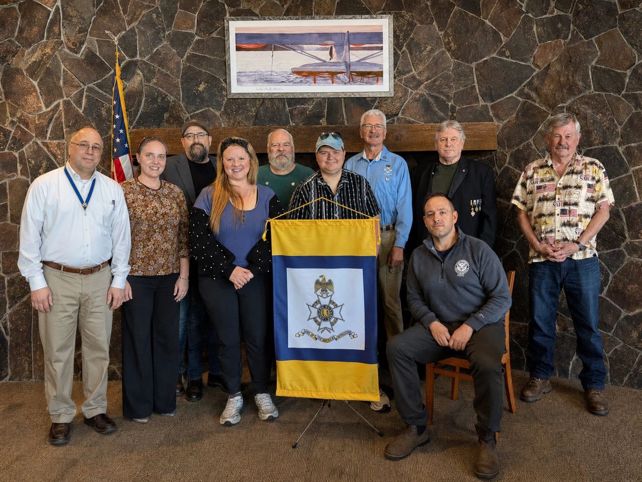 Group of people posing with a banner in front of a stone wall.