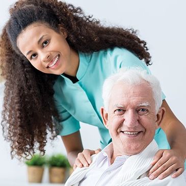 Smiling caregiver with elderly man in a bright room.
