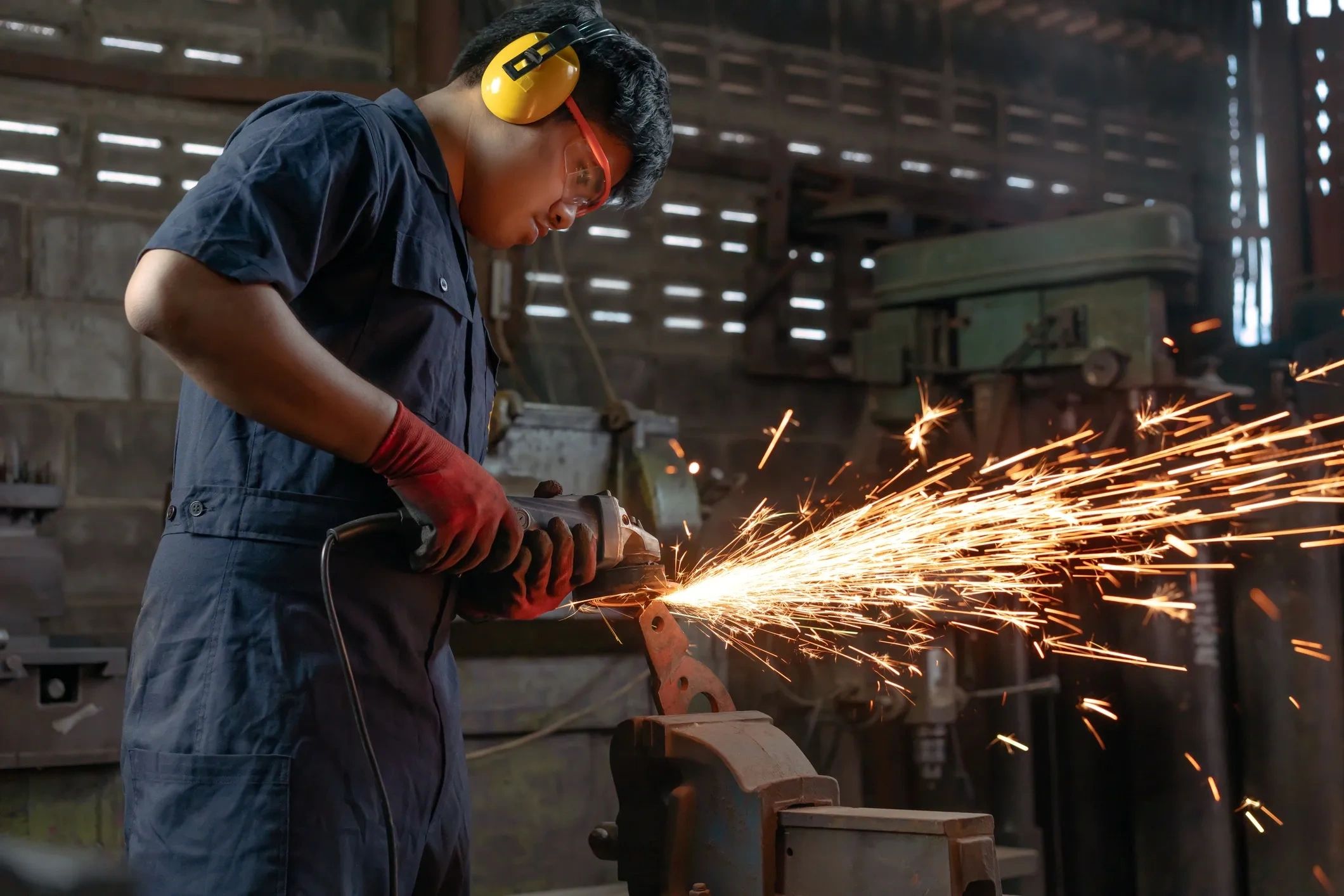 Worker grinding metal with sparks flying.